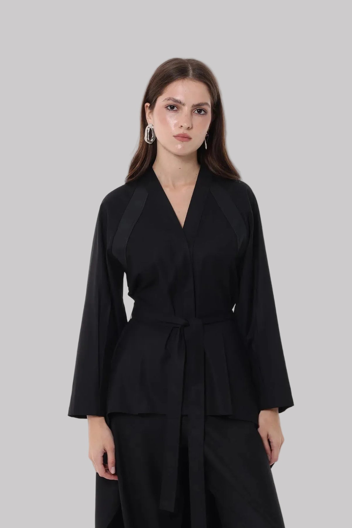 A black long-sleeve wrap-style top with a self-tie waist belt, photographed against a plain white studio background.